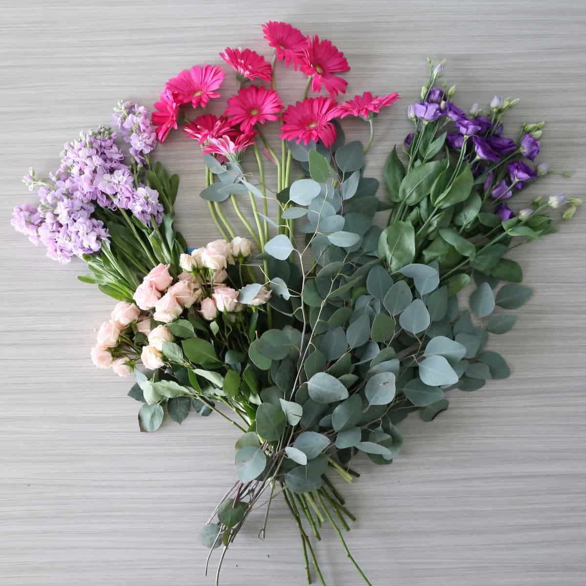 pink mauve bulk flower bundle 5 varieties roses gerbera lisianthus stock eucalyptus flat lay